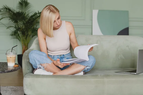 Güzel sarışın kadın oturma odasında dergi okuyor.. — Stok fotoğraf