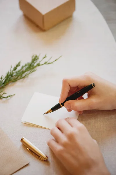 Female hands writing Christmas card on wooden table. — Φωτογραφία Αρχείου