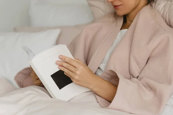 Όμορφη γυναίκα ξαπλωμένη στο κρεβάτι και την ανάγνωση ενός βιβλίου. — Φωτογραφία Αρχείου