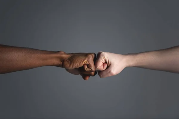 Close up of white skinned man and dark skinned man doing a fist bump. — Stock Photo, Image