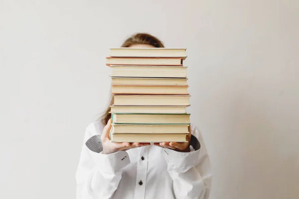 Genç kız öğrenci kitap yığınının arkasına saklanıyor..