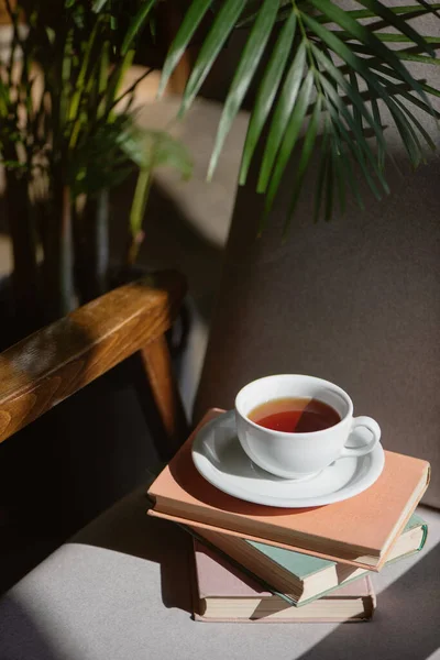 Tumpukan buku dengan cangkir teh di kursi. — Stok Foto