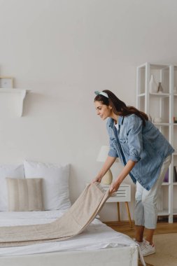 Genç bir kadın yatağını yapıyor..