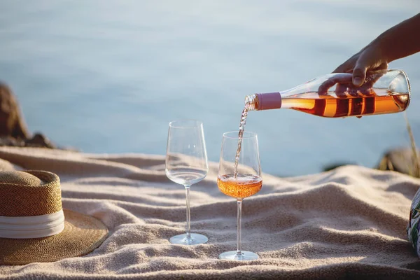 Frau gießt am Strand Rosenwein aus Flasche in Gläser. — Stockfoto