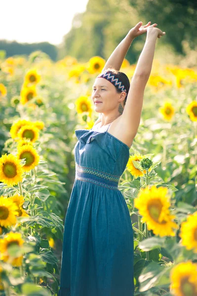 Junge Frau auf Sonnenblumenfeld — Stockfoto
