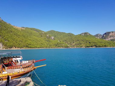 Güneşli, bulutsuz bir günde, dağların arka planına karşı deniz manzarası.