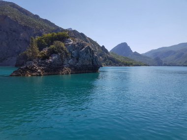 Güneşli, bulutsuz bir günde, dağların arka planına karşı deniz manzarası.