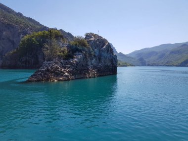 Güneşli, bulutsuz bir günde, dağların arka planına karşı deniz manzarası.
