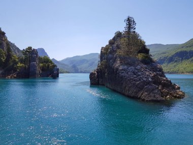 Güneşli, bulutsuz bir günde, dağların arka planına karşı deniz manzarası.