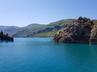 Güneşli, bulutsuz bir günde, dağların arka planına karşı deniz manzarası.