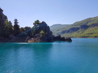 Güneşli, bulutsuz bir günde, dağların arka planına karşı deniz manzarası.