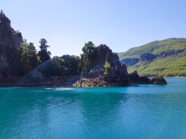 Güneşli, bulutsuz bir günde, dağların arka planına karşı deniz manzarası.