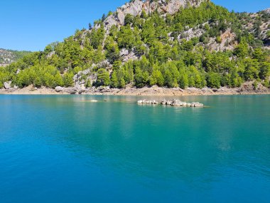 Güneşli, bulutsuz bir günde, dağların arka planına karşı deniz manzarası.