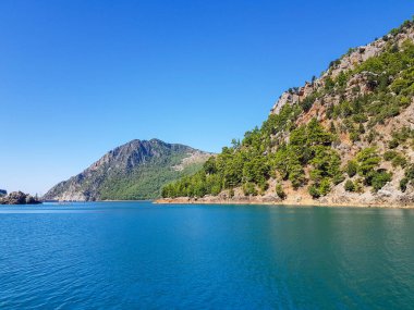 Güneşli, bulutsuz bir günde, dağların arka planına karşı deniz manzarası.