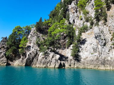 Güneşli, bulutsuz bir günde, dağların arka planına karşı deniz manzarası.