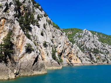 Güneşli, bulutsuz bir günde, dağların arka planına karşı deniz manzarası.