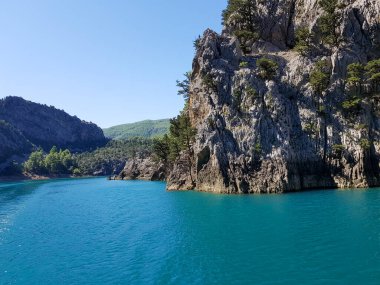 Güneşli, bulutsuz bir günde, dağların arka planına karşı deniz manzarası.