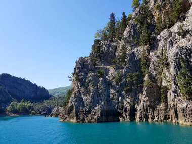 Güneşli, bulutsuz bir günde, dağların arka planına karşı deniz manzarası.