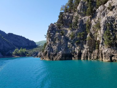 Güneşli, bulutsuz bir günde, dağların arka planına karşı deniz manzarası.