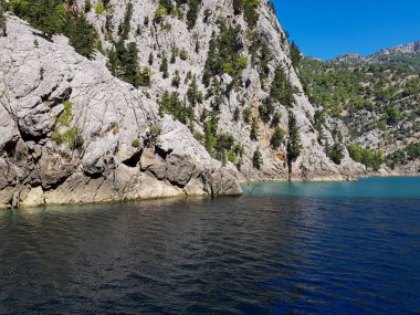 Güneşli, bulutsuz bir günde, dağların arka planına karşı deniz manzarası.