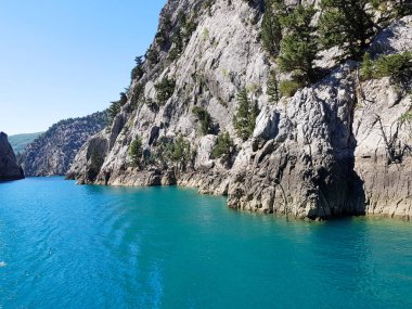 Güneşli, bulutsuz bir günde, dağların arka planına karşı deniz manzarası.