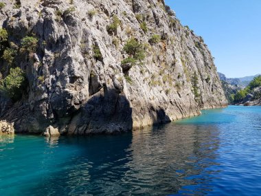 Güneşli, bulutsuz bir günde, dağların arka planına karşı deniz manzarası.