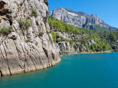 Güneşli, bulutsuz bir günde, dağların arka planına karşı deniz manzarası.