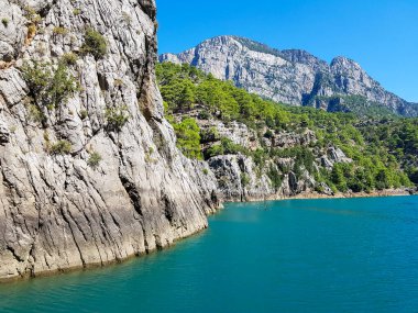 Güneşli, bulutsuz bir günde, dağların arka planına karşı deniz manzarası.