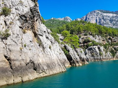 Güneşli, bulutsuz bir günde, dağların arka planına karşı deniz manzarası.