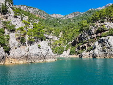 Güneşli, bulutsuz bir günde, dağların arka planına karşı deniz manzarası.