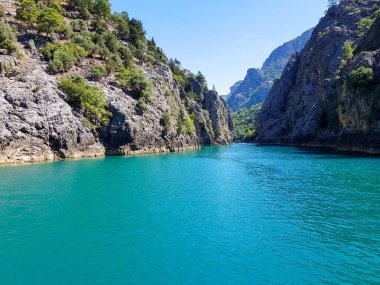 Güneşli, bulutsuz bir günde, dağların arka planına karşı deniz manzarası.
