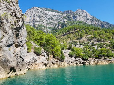 Güneşli, bulutsuz bir günde, dağların arka planına karşı deniz manzarası.