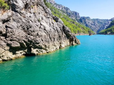 Güneşli, bulutsuz bir günde, dağların arka planına karşı deniz manzarası.