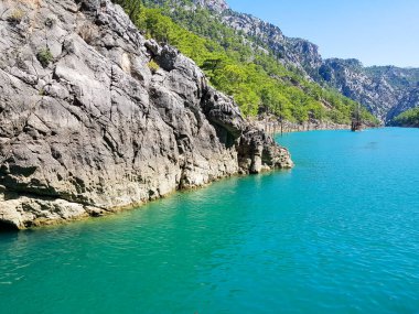 Güneşli, bulutsuz bir günde, dağların arka planına karşı deniz manzarası.