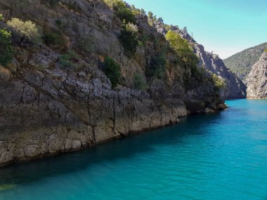 Güneşli, bulutsuz bir günde, dağların arka planına karşı deniz manzarası.