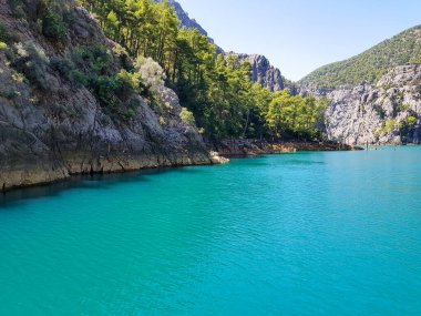 Güneşli, bulutsuz bir günde, dağların arka planına karşı deniz manzarası.