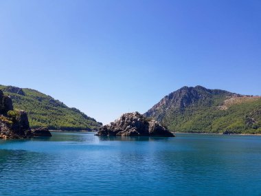 Güneşli, bulutsuz bir günde, dağların arka planına karşı deniz manzarası.