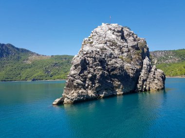 Güneşli, bulutsuz bir günde, dağların arka planına karşı deniz manzarası.