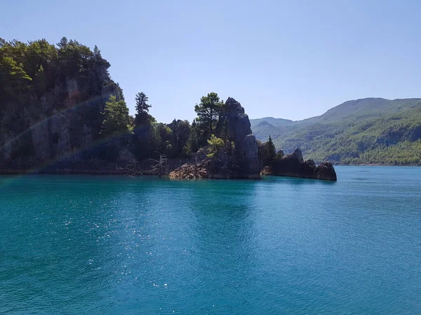 Güneşli, bulutsuz bir günde, dağların arka planına karşı deniz manzarası.