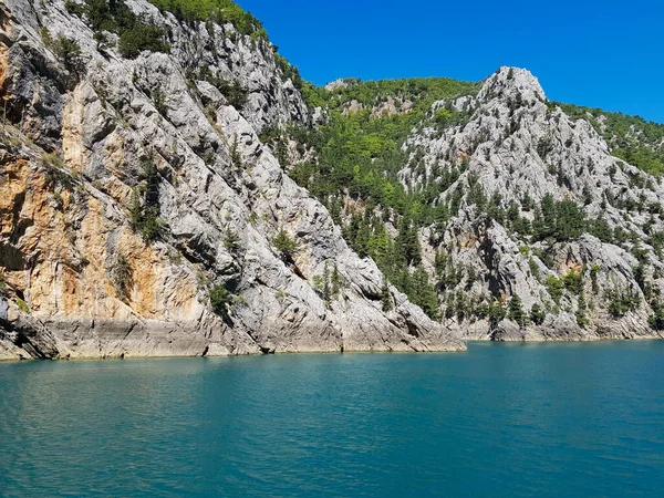 Güneşli, bulutsuz bir günde, dağların arka planına karşı deniz manzarası.