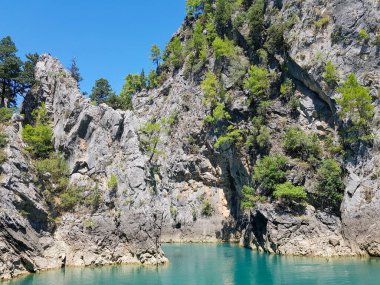 Güneşli, bulutsuz bir günde, dağların arka planına karşı deniz manzarası.