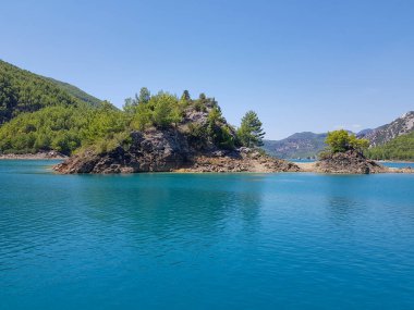 Güneşli, bulutsuz bir günde, dağların arka planına karşı deniz manzarası.