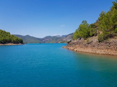Güneşli, bulutsuz bir günde, dağların arka planına karşı deniz manzarası.