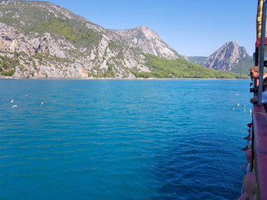 Güneşli, bulutsuz bir günde, dağların arka planına karşı deniz manzarası.