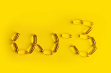 Sarı arkaplanda omega 3 jel kapsülleri