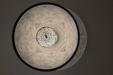 Doğal arka plan veya doku olarak alçı ve siyah süslemeli beyaz yuvarlak lamba yakın plan