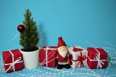 Kırmızı ve beyaz hediye kutularıyla Noel afişi, Noel Baba ve mavi arka planda Noel ağacı