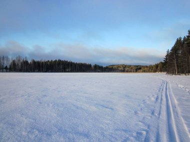 Karla kaplı orman gölü güneşli, soğuk bir günde, kar aracı kış bayrağı olarak kullanılıyor.