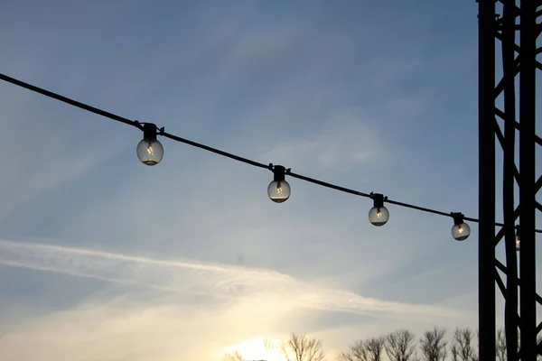 Close Van Een Slinger Van Gloeilampen Tegen Een Zonsondergang Hemel — Stockfoto