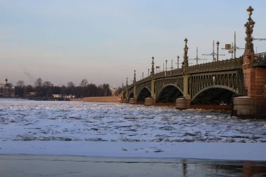 Güneşli bir kış gününde, köprünün yakınındaki çimenli yolun kenarındaki nehirde buzdan hummock sesleri. 